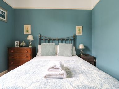 A bedroom with a double bed with pillows and folded towels and wooden bedside tables with lamps at Dale House in Lorton