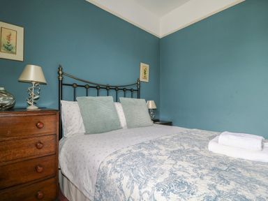 A bedroom with a metal bed frame wooden chest of drawers and two lamps at Dale House in Lorton