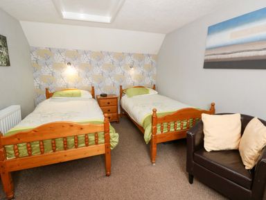 A bedroom with two single beds and a chair at Old Farmhouse Cottage