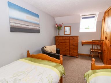A bedroom with two beds, a chest of drawers and a window at Old Farmhouse Cottage