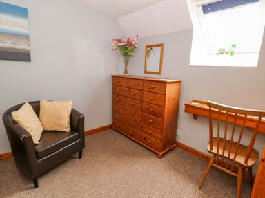 A bedroom with a dresser, mirror, chair, and a painting at Old Farmhouse Cottage