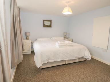 A bedroom with a double bed two bedside tables lamps and folded towels at 2 Park Nook Close in Waberthwaite