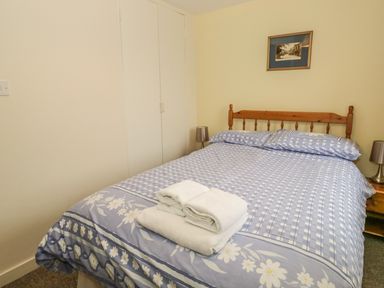 A bedroom with a double bed with blue floral bedding and towels on the bed at 2 Park Nook Close in Waberthwaite