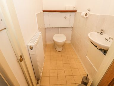 A small bathroom with a toilet, a sink, a radiator, and a toilet paper holder at 2 Park Nook Close in Waberthwaite