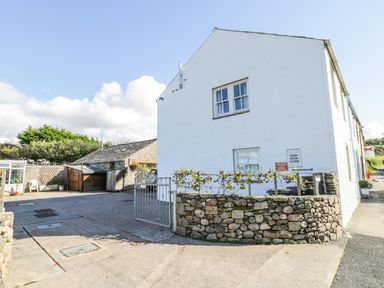 A white building with windows and a stone wall with a metal gate at 1 Park Nook Close in Waberthwaite