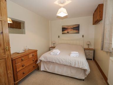 A bedroom with a double bed and wooden furniture at 1 Park Nook Close in Waberthwaite