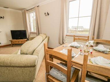 A living room with a dining table set and a television at 1 Park Nook Close in Waberthwaite