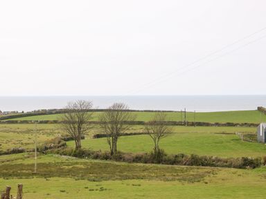 A rural landscape with fields trees and a coastline at Coetsiws in Clynnog Fawr