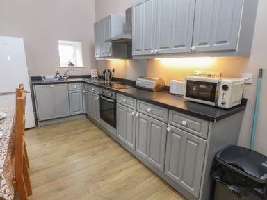 A kitchen with cupboards and appliances at Coetsiws in Clynnog Fawr