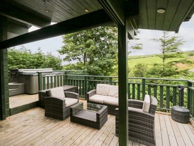 A deck with outdoor furniture and a hot tub at Oak Lodge in Pennington near Ulverston