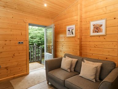 A snug area with a sofa and door leading outside at Oak Lodge Pennington near Ulverston
