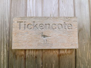 A wooden sign with the word Tickencote and a bird design mounted on a wooden surface at Tickencote Exton Rutland