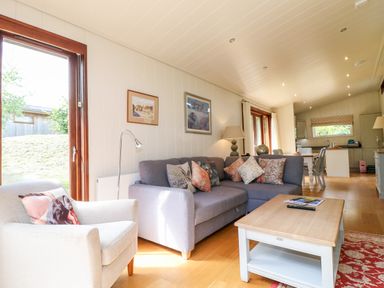 A living room with a gray sofa and an armchair with cushions and a wooden coffee table at Tickencote in Exton Rutland