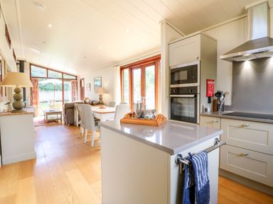 A kitchen and dining area with an island and chairs and a living room with sofa and lamp at Tickencote in Exton Rutland