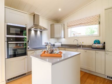 A kitchen with an island a built in oven microwave a sink and countertop appliances at Tickencote in Exton Rutland