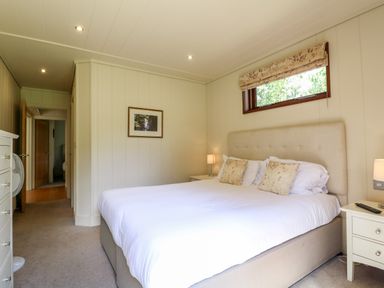 A bedroom with a large bed bed side tables lamps and a window with a roman blind at Tickencote in Exton Rutland