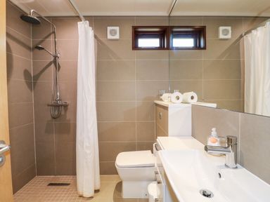 A bathroom with a shower area with curtain toilet and sink with mirror at Tickencote Exton Rutland