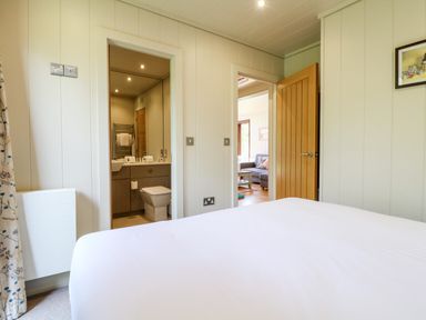 A bedroom with bed and open doors leading to a bathroom and living room at Tickencote in Exton Rutland
