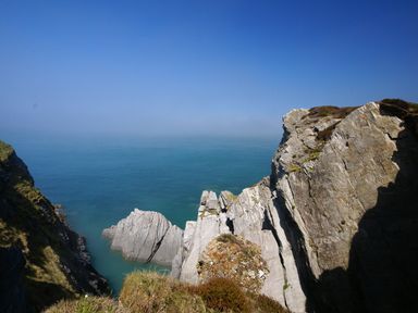 A view of rocky cliffs overlooking the sea with clear blue sky at Seal Cottage in Mortehoe