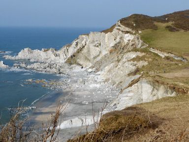 A rocky coastal cliff with a small beach and steps leading down to the shore at Seal Cottage in Mortehoe
