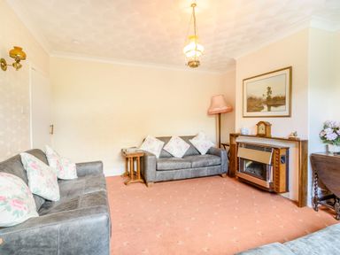 A living room with two sofas floral cushions a fireplace a painting and a floor lamp at The Perks in Scarborough