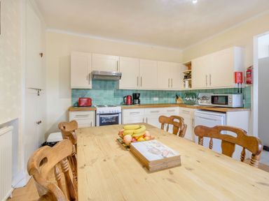 A kitchen with wooden table and chairs fruit bowl stove microwave and cabinets at The Perks in Scarborough