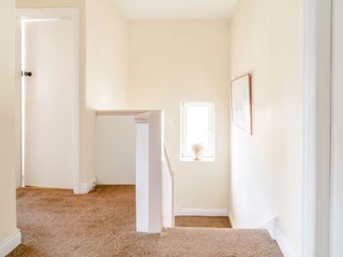 A stairway landing with brown carpet a small window with a globe and a closed door at The Perks in Scarborough