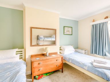 A bedroom with two single beds a wooden dresser with a lamp and a mirror on the wall at The Perks in Scarborough