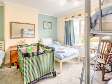 A bedroom with single beds a playpen a rocking chair and bunk bed at The Perks in Scarborough