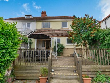 A backyard with wooden deck steps leading to a patio with a table and umbrella at The Perks in Scarborough