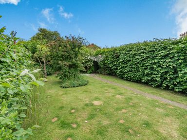 A garden with a grass lawn a clothesline a tree and hedges at The Perks in Scarborough