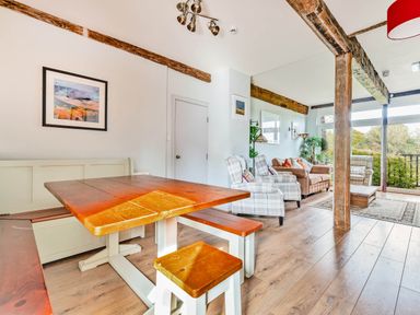 A dining area with a wooden table and bench and a living area with armchairs and a sofa by windows at Eden Mill Millers Beck in Kendal