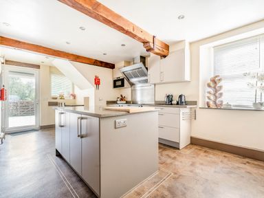 A kitchen with cabinets an island and wooden beams at Eden Mill Millers Beck in Kendal