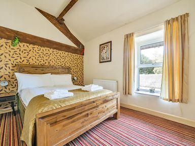 A bedroom with a wooden bed and striped carpet at Eden Mill Millers Beck in Kendal