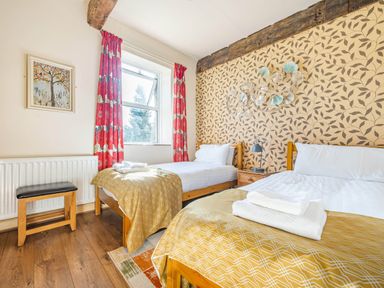 A bedroom with two single beds and yellow patterned blankets at Eden Mill Millers Beck in Kendal