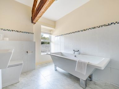 A bathroom with a white bathtub a toilet and a window at Eden Mill Millers Beck in Kendal