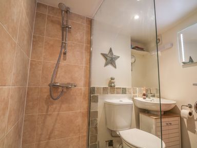 A bathroom with a shower, toilet, sink, and a star decoration on the wall at The Compass in Swanage