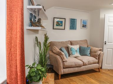 A sofa with cushions and framed pictures on the wall in a living room at The Compass in Swanage