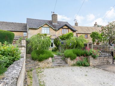 A stone cottage with a garden and steps leading up to the entrance at Puffitts Cottage in Bourton-on-the-Water