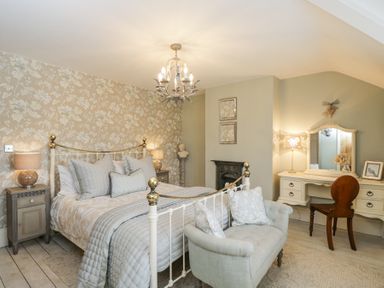 A bedroom with a metal bed a small couch bedside tables and a dressing table at Puffitts Cottage in Bourton-on-the-Water