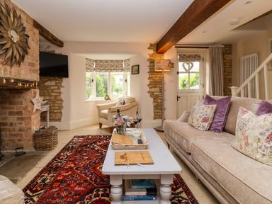 A living room with a sofa, coffee table, and fireplace at Puffitts Cottage in Bourton-on-the-Water