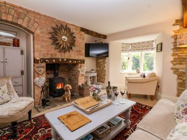 A living room with a wood stove and a coffee table at Puffitts Cottage in Bourton-on-the-Water