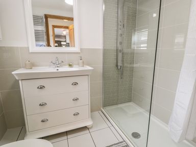 A bathroom with a white vanity sink, a mirror, and a glass-enclosed shower at Garreg Ddu in Blaenau Ffestiniog