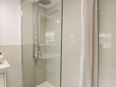 A shower area with a glass panel and rain showerhead in a bathroom at Garreg Ddu in Blaenau Ffestiniog
