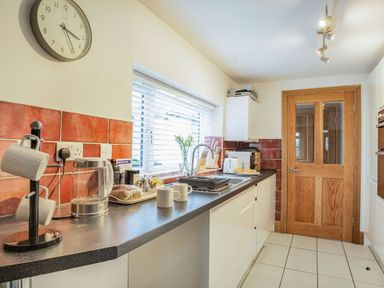 A kitchen with a wooden door countertop appliances and two cups on the counter at Garreg Ddu Blaenau Ffestiniog