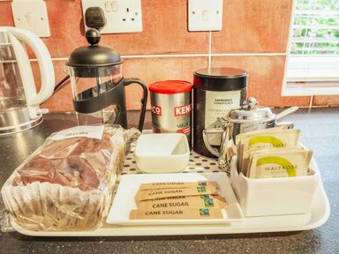 A kitchen countertop with a kettle coffee press coffee tins sugar packets and tea bags at Garreg Ddu in Blaenau Ffestiniog