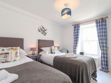 A bedroom with two single beds and blue check curtains at Mermaid Cottage in Mousehole