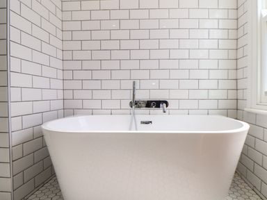 A bathroom with a white freestanding bathtub and white subway tiled walls at Mermaid Cottage in Mousehole