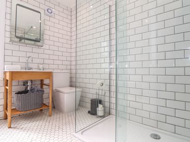 A bathroom with a wooden sink vanity a mirror toilet and glass shower enclosure at Mermaid Cottage in Mousehole