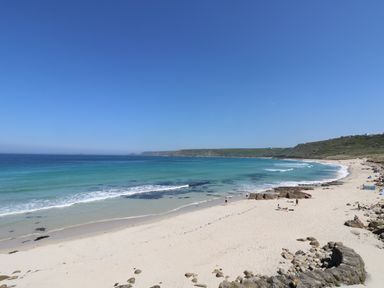 A sandy beach with people near the shoreline and turquoise water at Mermaid Cottage in Mousehole